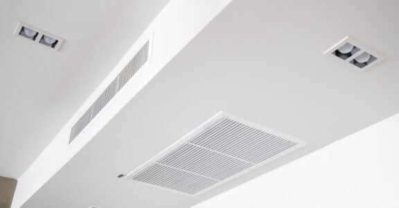 Plafond avec aérations rectangulaires et éclairage encastré.