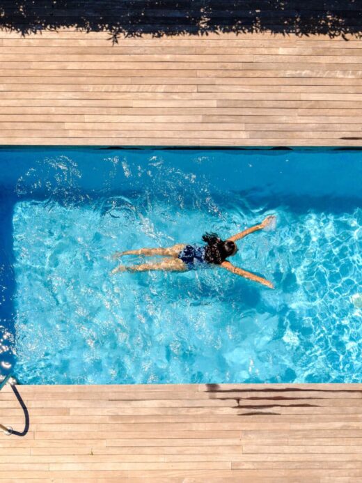 Une personne dans une piscine, terrasse en bois entourant.